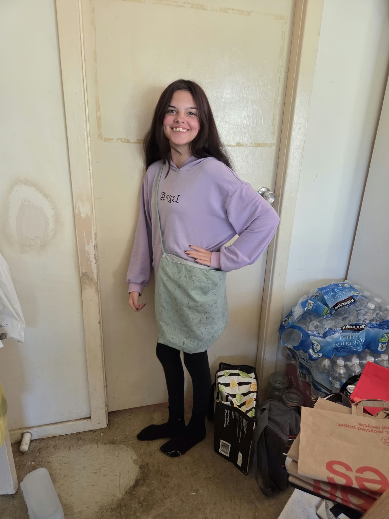 A smiling young woman showing off the bag she sewed herself